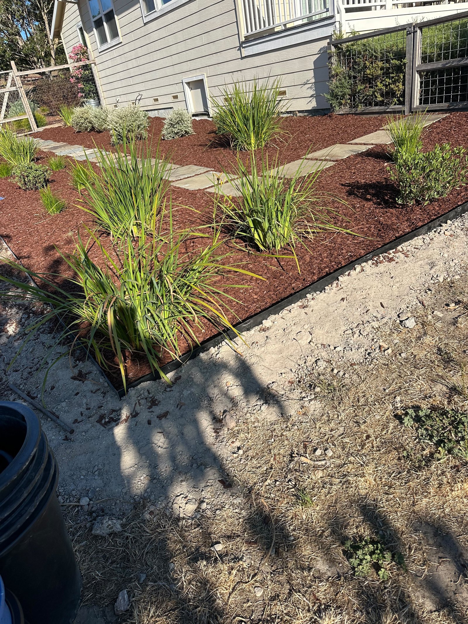 Gray tumbled-paver patio with three block steps between raised garden beds